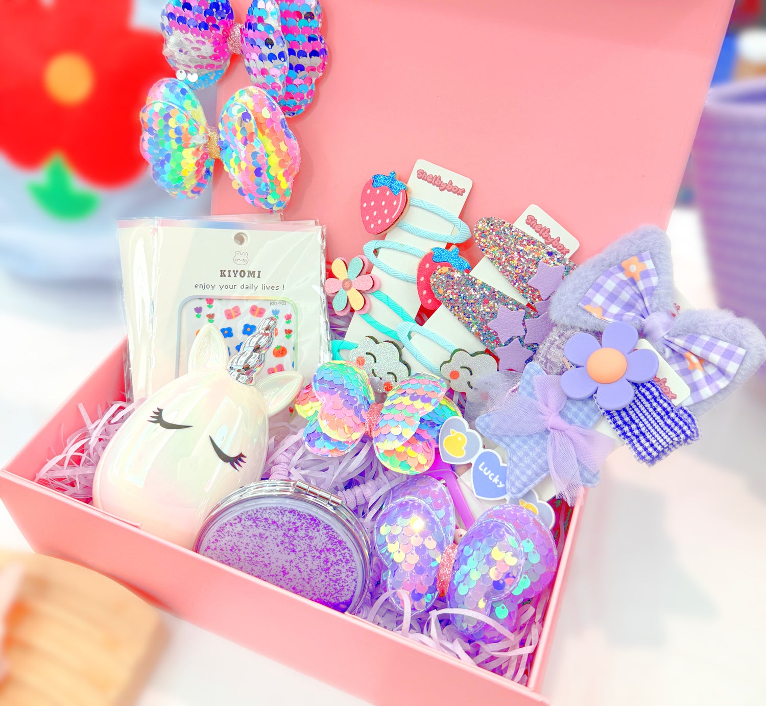 A gift set containing various purple hair accessories including clips, ties, and a comb, presented in a pink box with a clear display window.